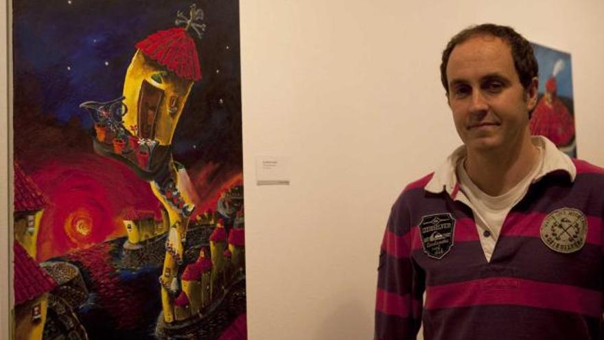 Javier Antuña, con una de sus obras en una exposición en Sama.