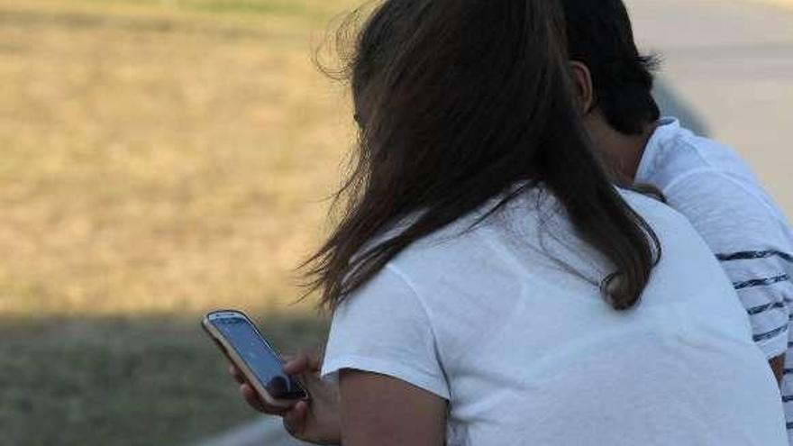 Dos adolescentes con un teléfono móvil.