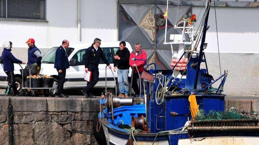 Un barco de la vieira atracado en Tragove pasadas las 15 horas, junto a los inspectores de la Xunta. // IA.