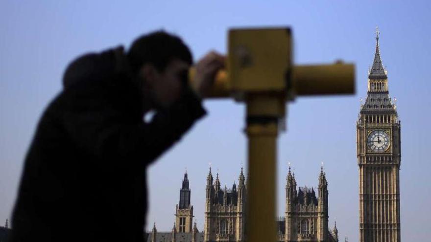 Un turista en Londres mira por un telescopio frente al Big Ben.