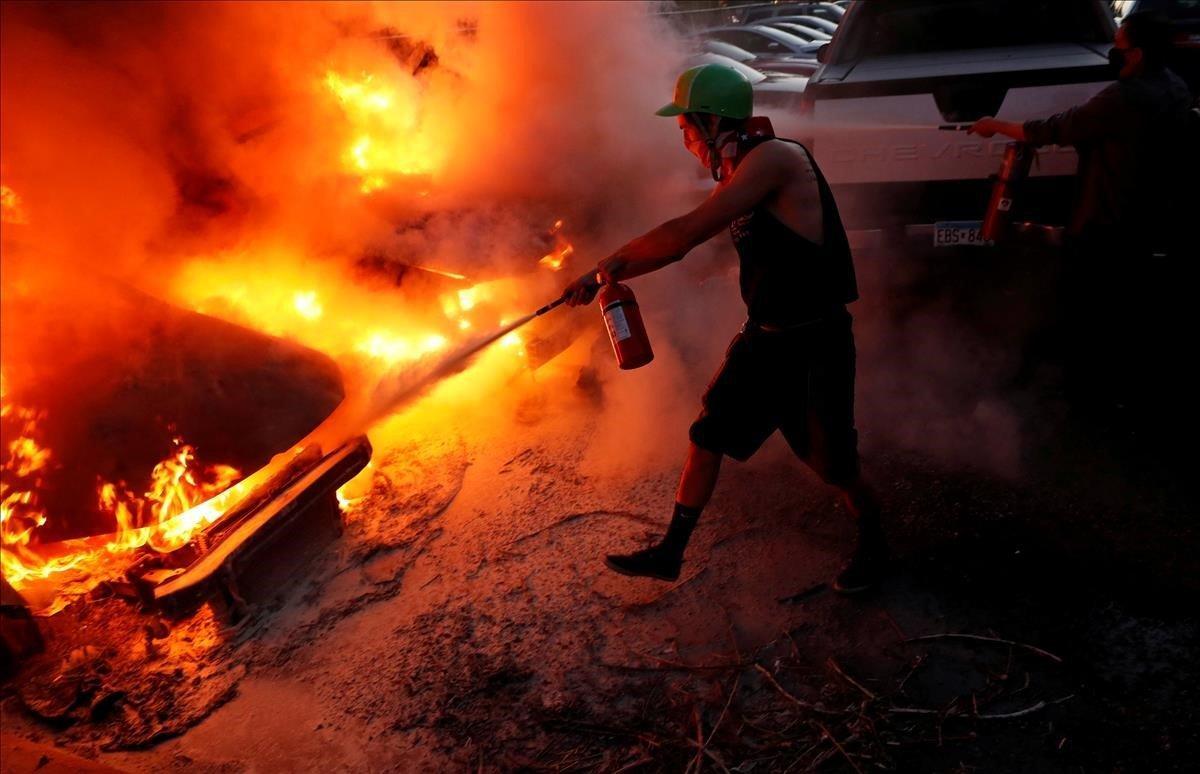 Manifestantes intentan extinguir el fuego en unos vehículos durante la manifestación en Minneapolis.