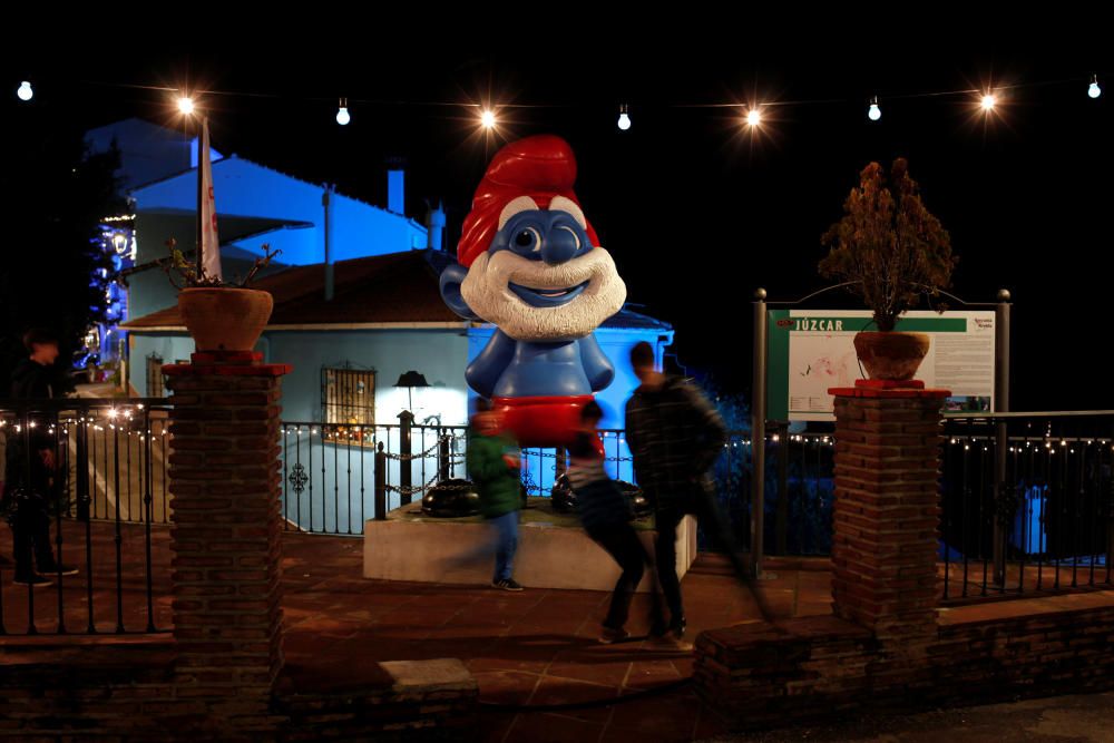 Children play with a ball next to a smurf statue ...