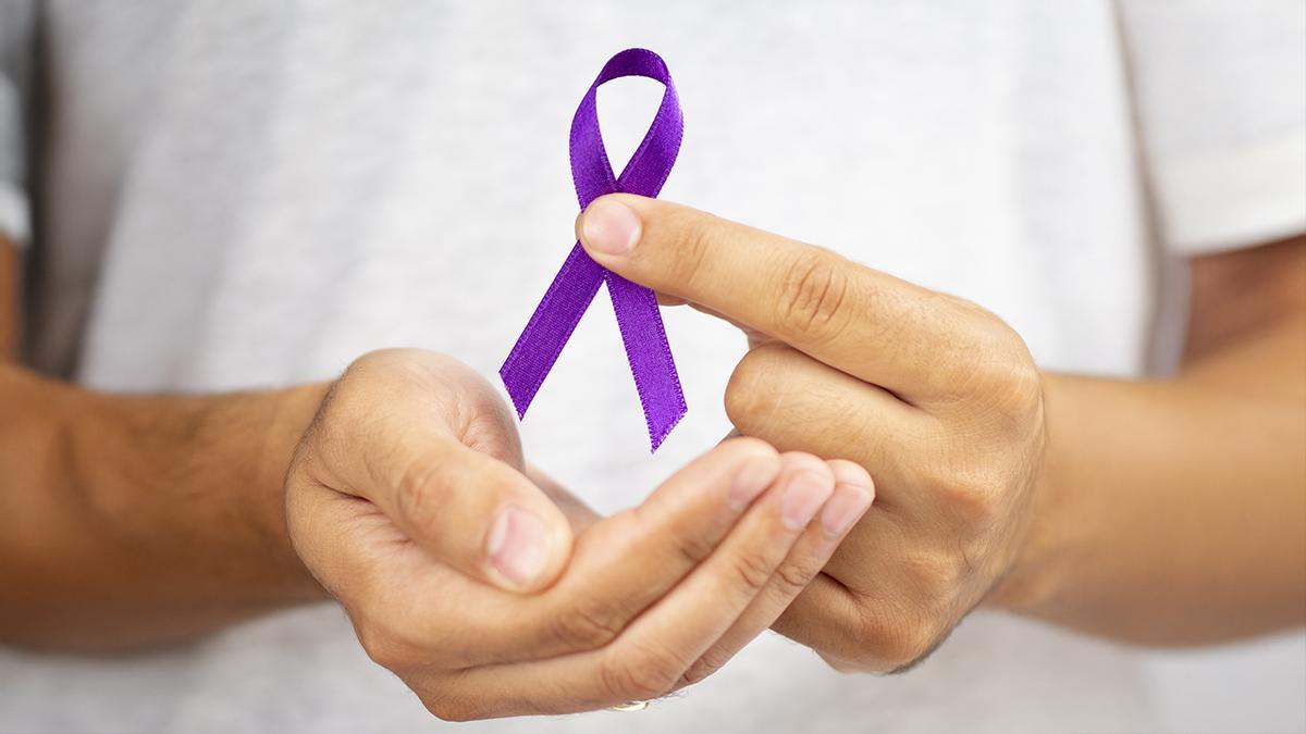 Manos sosteniendo el lazo violeta del Día Mundial del Cáncer