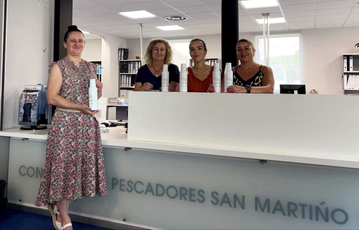 Trabajadoras de la cofradía de pescadores San Martiño muestran las botellas reutilizables que se reparten entre los socios.
