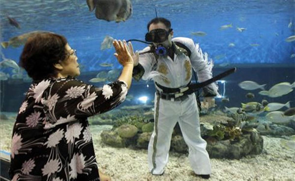 Una turista encaixa la mà a un bus vestit d’Elvis Presley que mira d’amenitzar l’estada dels visitants de l’Ocean Park de Manila, a les Filipines.