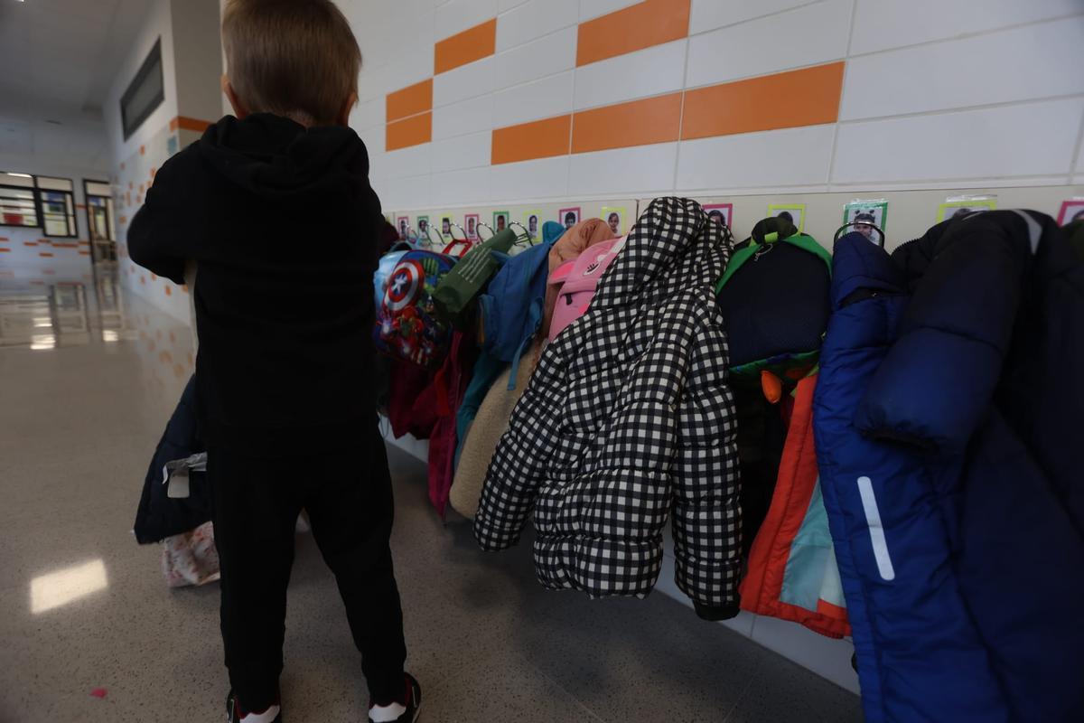 Un niño coloca su abrigo a la entrada de su clase.