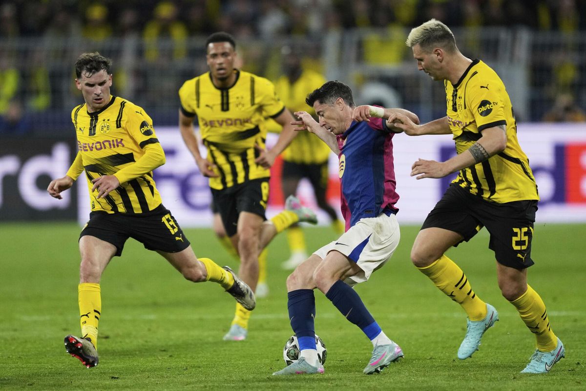 Barcelonas Robert Lewandowski, second right, duels for the ball with Dortmunds Niklas Suele, right, during the Champions League quarterfinals second leg soccer match between Borussia Dortmund and Barcelona, at the Signa-Iduna Park in Dortmund, Germany, Tuesday, April 15, 2025. (AP Photo/Martin Meissner)