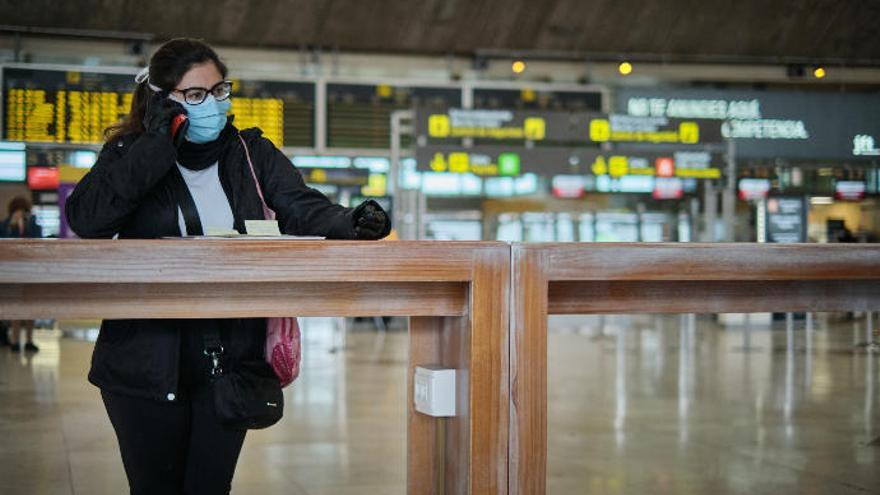 Una joven espera con una mascarilla en un aeropuerto tinerfeño.