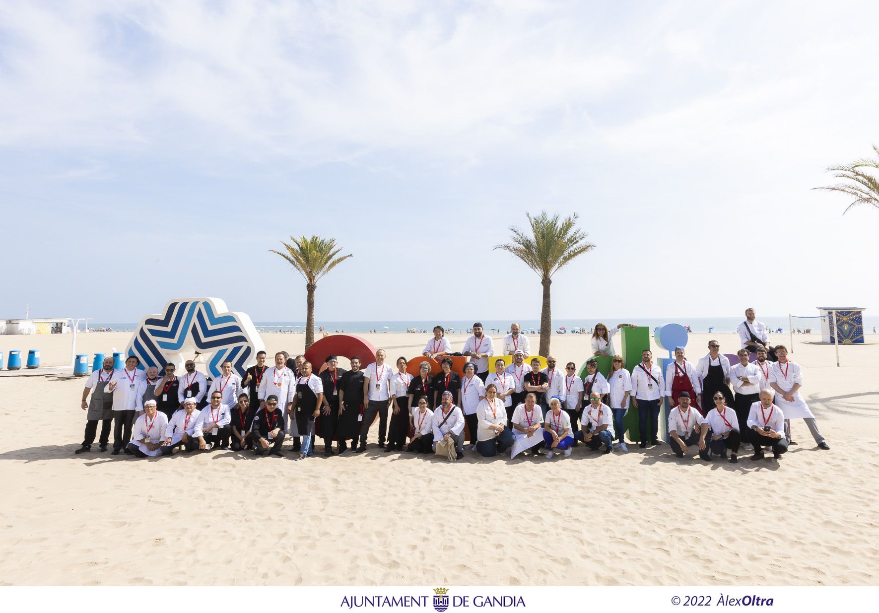 Todos los participantes del concurso, frente al cartel de Gandia en la playa.