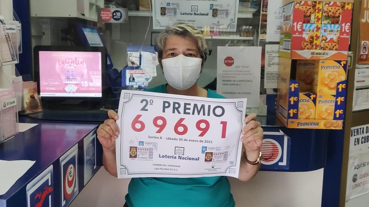 Guillermina Quintana con el cartel del segundo premio de la Lotería Nacional en su despacho receptor.