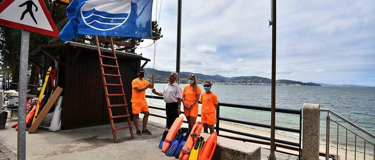 Luciano Sobral, alcalde de Poio, iza la bandera azul en la playa Cabeceira junto a los socorristas del arenal.