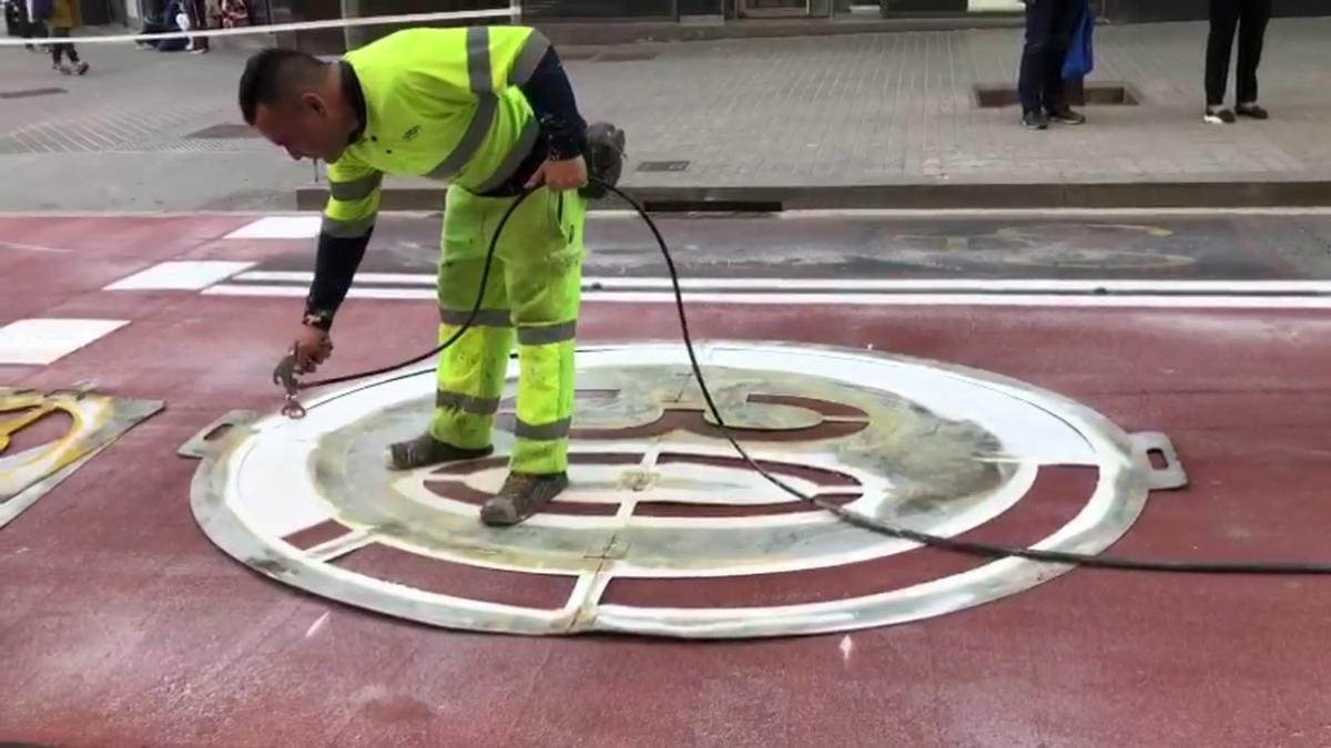 Operarios pintan señales de limitación de velocidad en el asfalto en la calle Borrell con Provença.