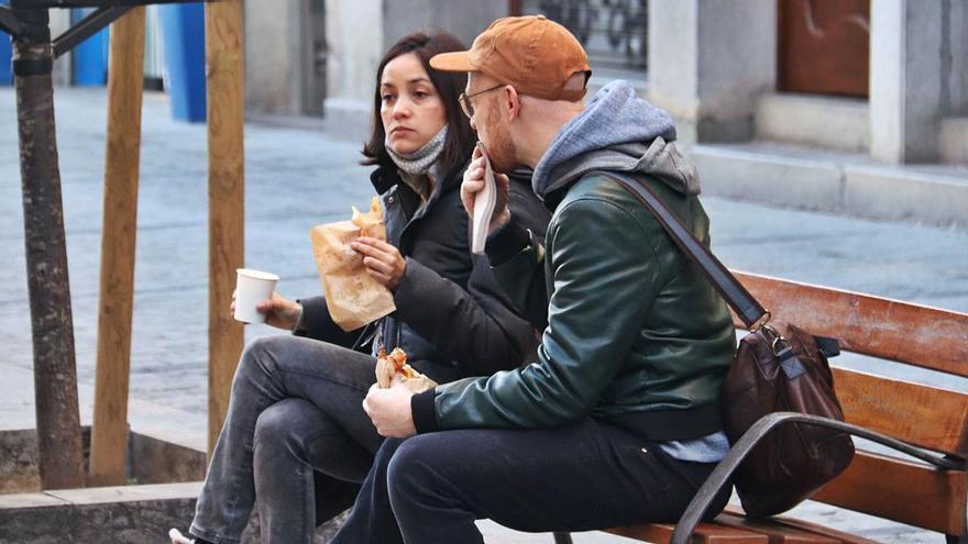 Una parella esmorzant en un banc públic de la Rambla de Girona.