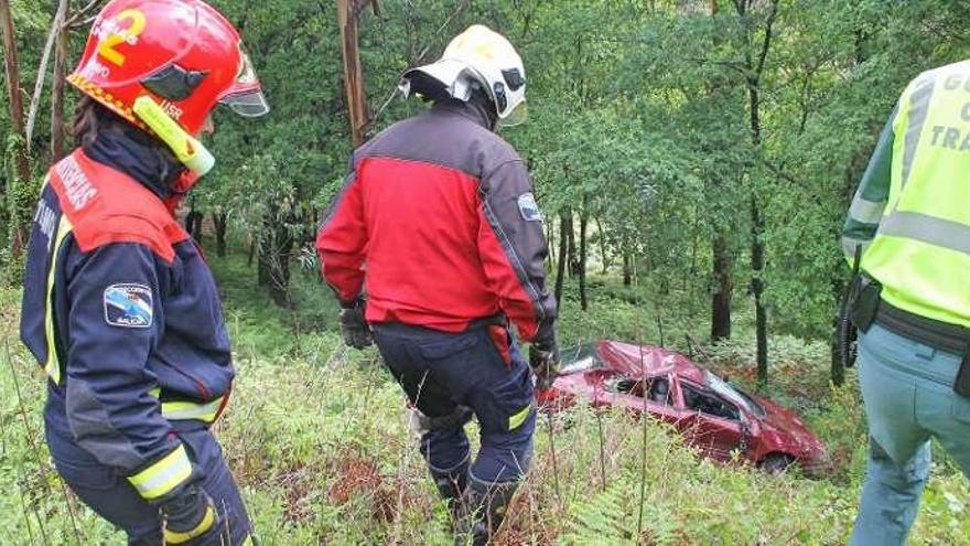 Miembros de Protección Civil y un agente de Tráfico bajan hacia el coche accidentado con el techo hundido posiblemente al dar una vuelta de campana tras salirse de la vía por el terraplén .  // Santos Álvarez