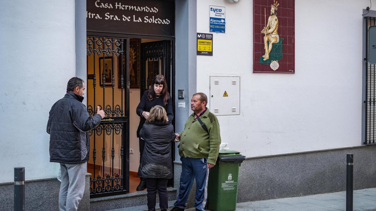 Tres personas recogen sus desayunos en la casa de hermandad de la Soledad, en la calle Santa Ana de Badajoz.