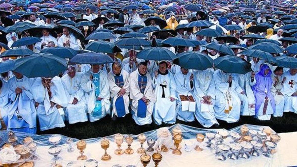 Sacerdotes polacos aguardan bajo sus paraguas el inicio de la misa en Cracovia, hace unos años, presidida por el entonces secretario de Estado del Vaticano, Angelo Sodano.