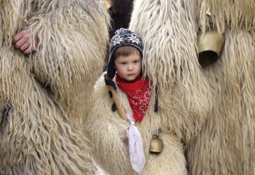 Un chico vestido con piel de oveja aguarda entre sus padres mientras observan el desfile durante el carnaval anual que marca el final del invierno en Litija.