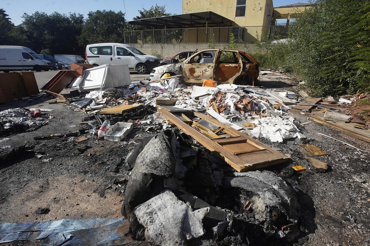 Un espai amb un munt de deixalles i un parell de vehicles cremats.