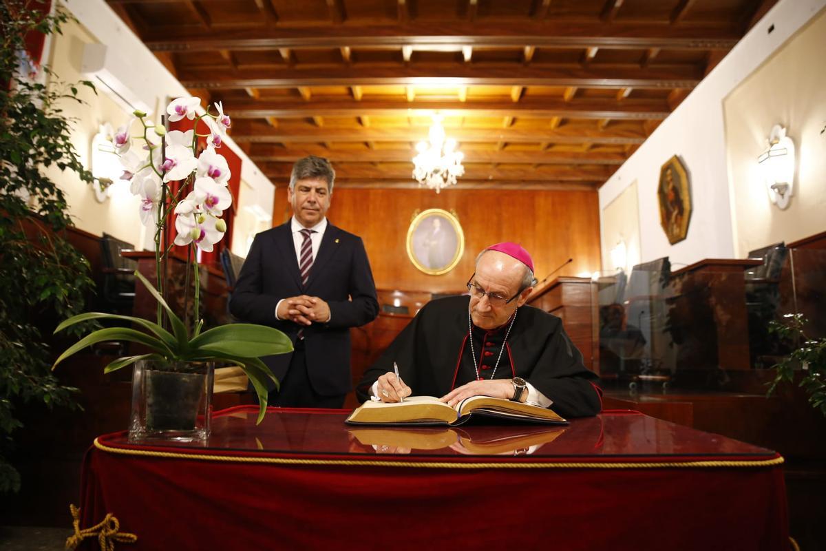El obispo firma en el Libro de Honor de Montilla en presencia del alcalde.