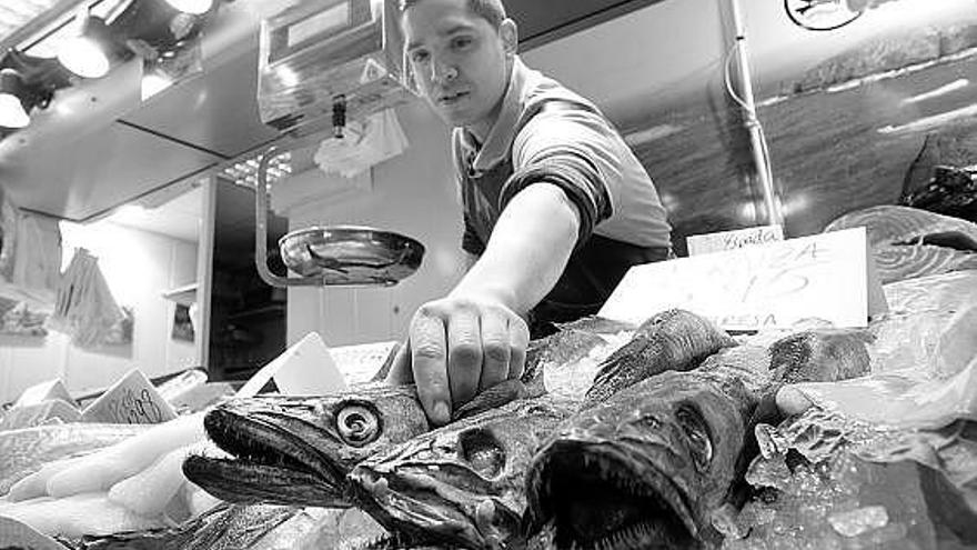 Gabriel Cobos, colocando unas merluzas, ayer, en su pescadería de la plaza de abastos de Avilés.