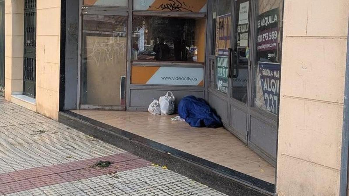 Una persona se cobija en un portal con un saco de dormir, en una calle de Badajoz.