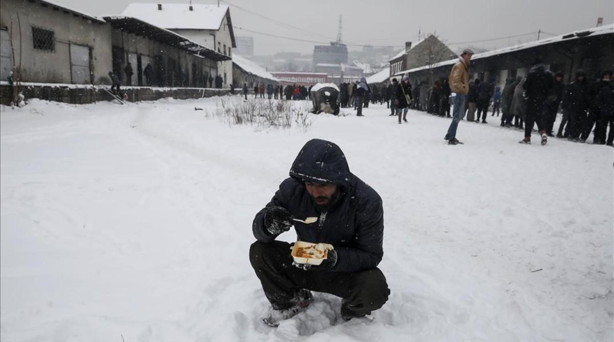 jjubierre36839922 a migrant eats a plate of free food during a snowfall outsid170111163459