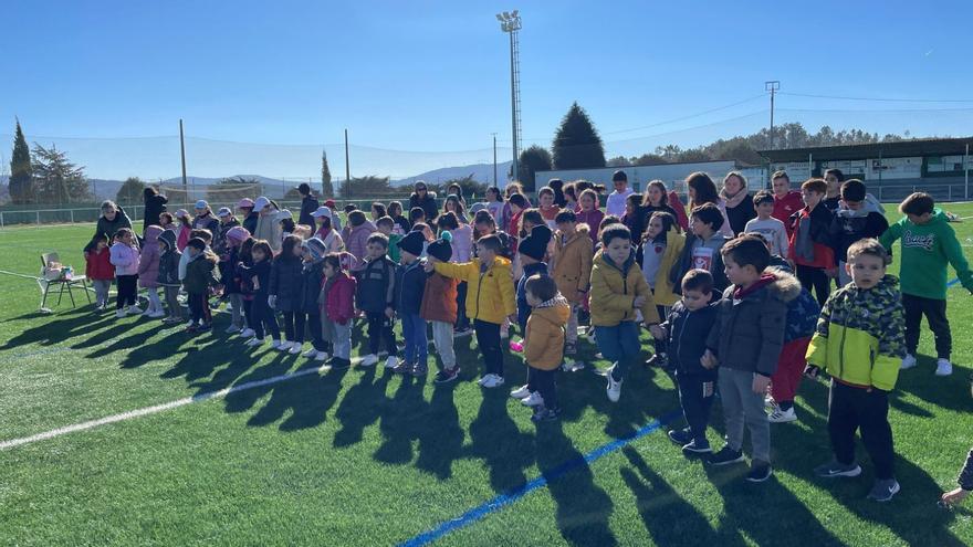 Alumnos, profesores y familias en el campo de fútbol de Forcarei durante la carrera solidaria.