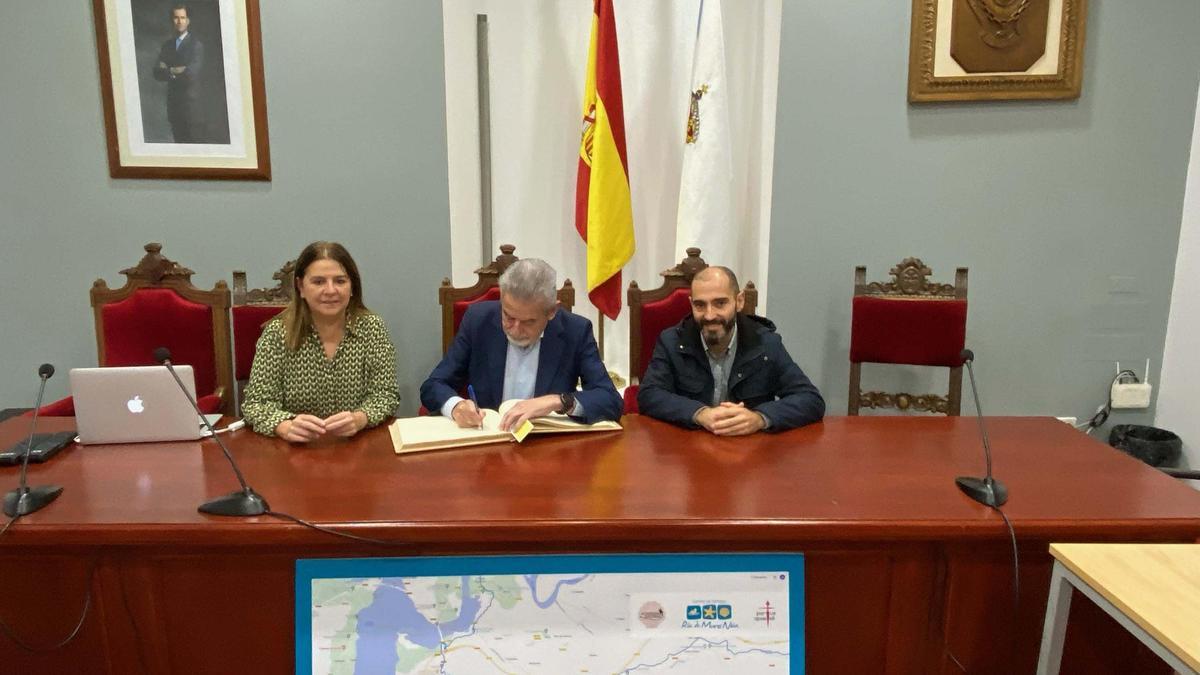 O presidente da Academia Xacobea, Xesús Palmou, asina no Libro de Honra de Noia flanqueado polos edís Marisol Villar e José Pérez.