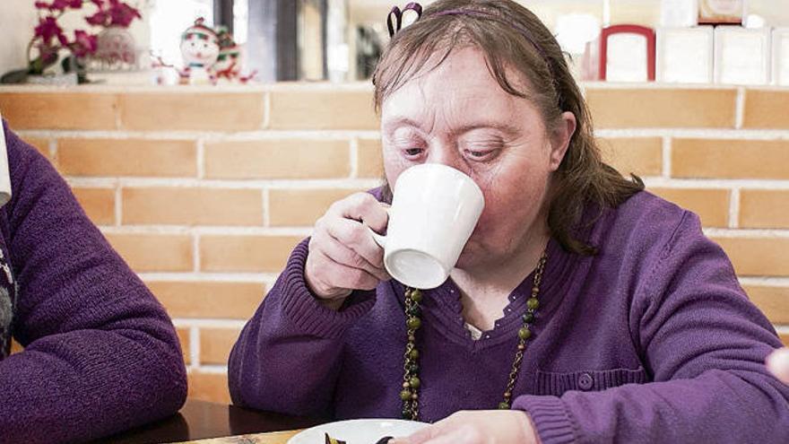 Isabel Ruiz, de 53 años y con síndrome de Down, se toma un café.