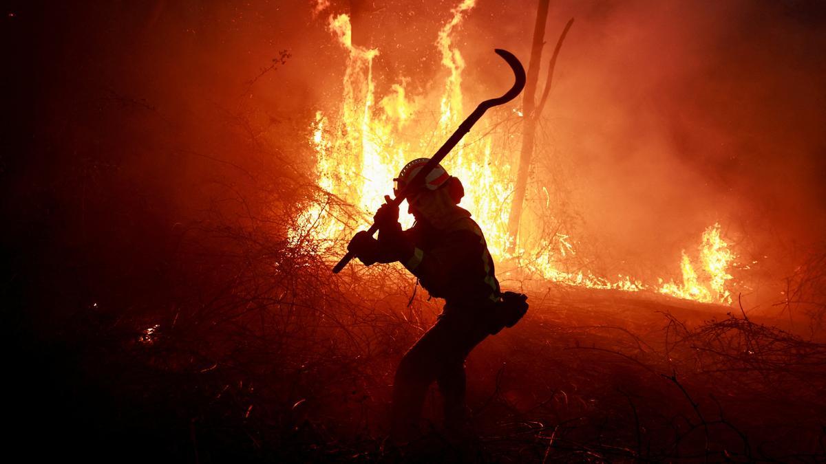 Un bombero combaten  las llamas durante un brote de incendios forestales, en Piedrafita, Asturias