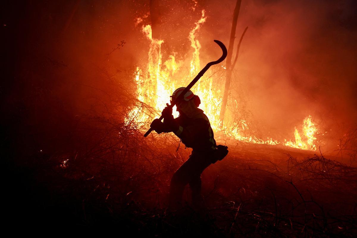 Un bombero gallego hace frente a las llamas en un bosque durante un brote de incendios forestales, en Piedrafita, Asturias