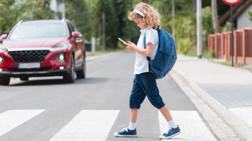 Un niño cruza la calle mientras mira el móvil