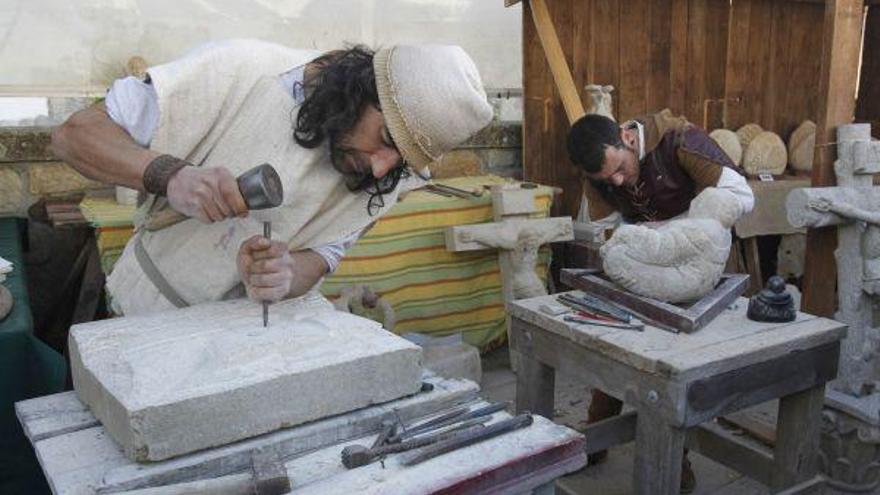 Dos canteros trabajando sobre la piedra.