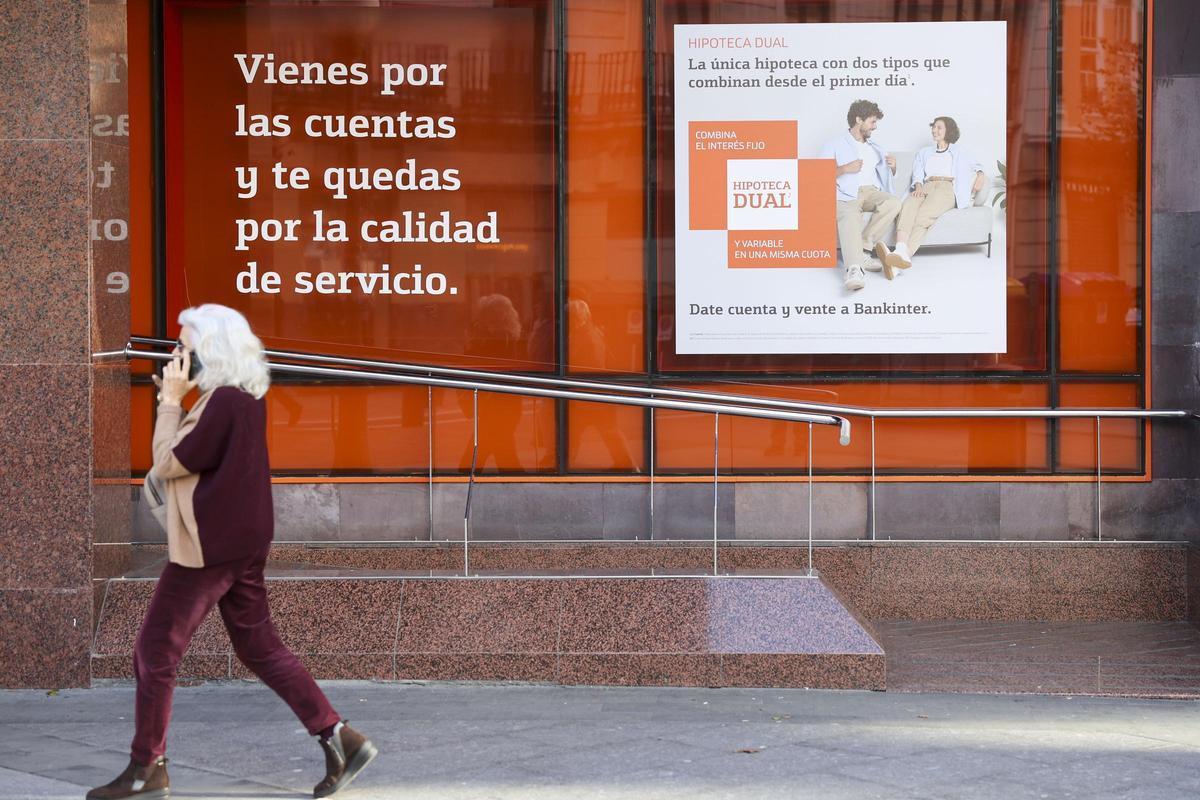 Una mujer pasa por delante de una sucursal bancaria.