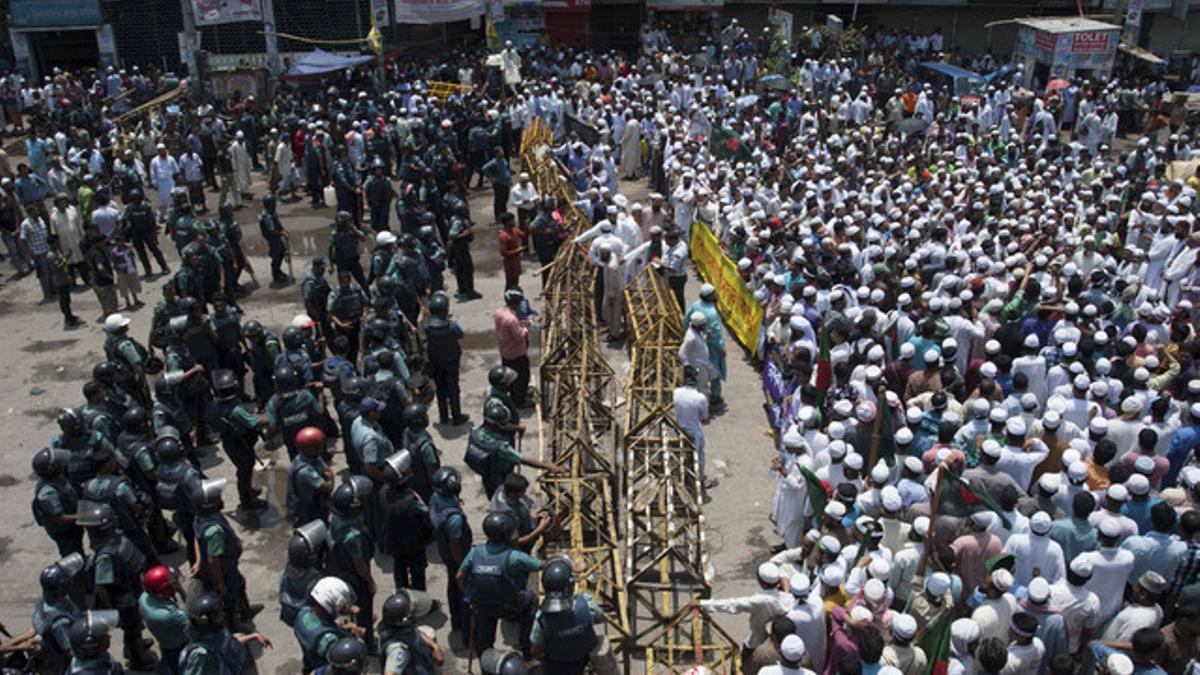 Cientos de islamistas, a la derecha, que bloquean una calle en Dacca, se enfrentran a la policía, el domingo.