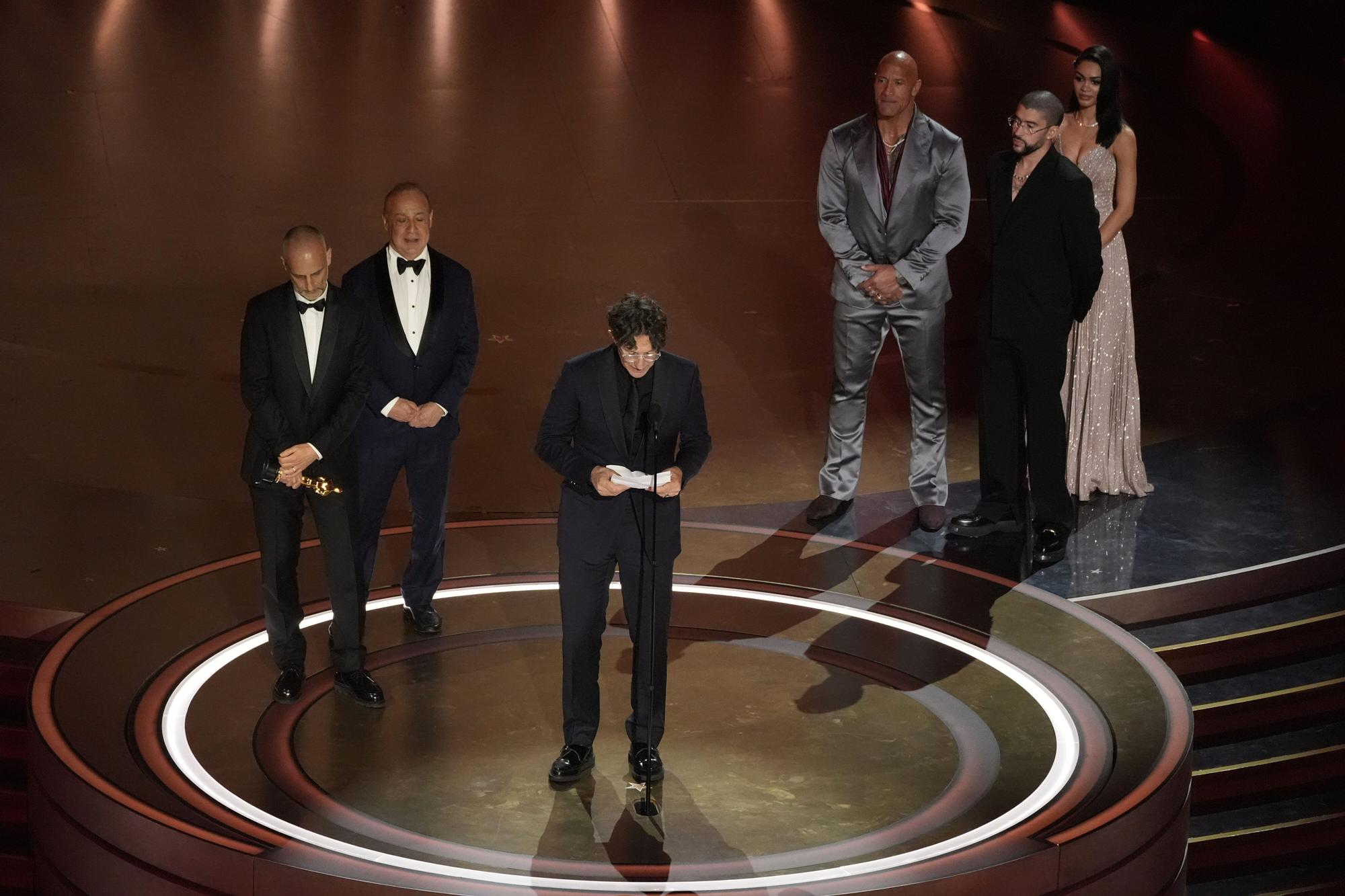 James Wilson, from left, Leonard Blavatnik, and Jonathan Glazer accept the award for "The Zone of Interest" from the United Kingdom, for best international feature film while Dwayne Johnson, and Bad Bunny look on during the Oscars on Sunday, March 10, 2024, at the Dolby Theatre in Los Angeles. (AP Photo/Chris Pizzello) Associated Press/LaPresse Only Italy and Spain / EDITORIAL USE ONLY/ONLY ITALY AND SPAIN