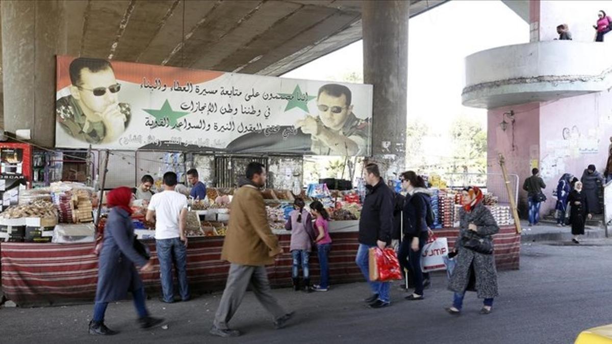 Sirios pasean por un mercado de Damasco tras el alto el fuego en Siria.