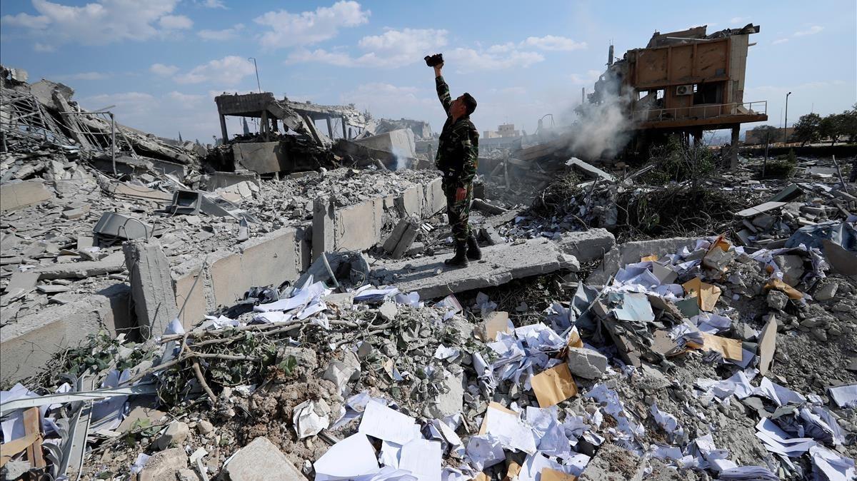 Un soldado sirio filma los escombros tras un ataque de las fuerzas estadounidenses, francesas y británicas el 14 de abril del 2018 para castigar al presidente Bashar el Asad por el uso de armas químicas contra civiles.