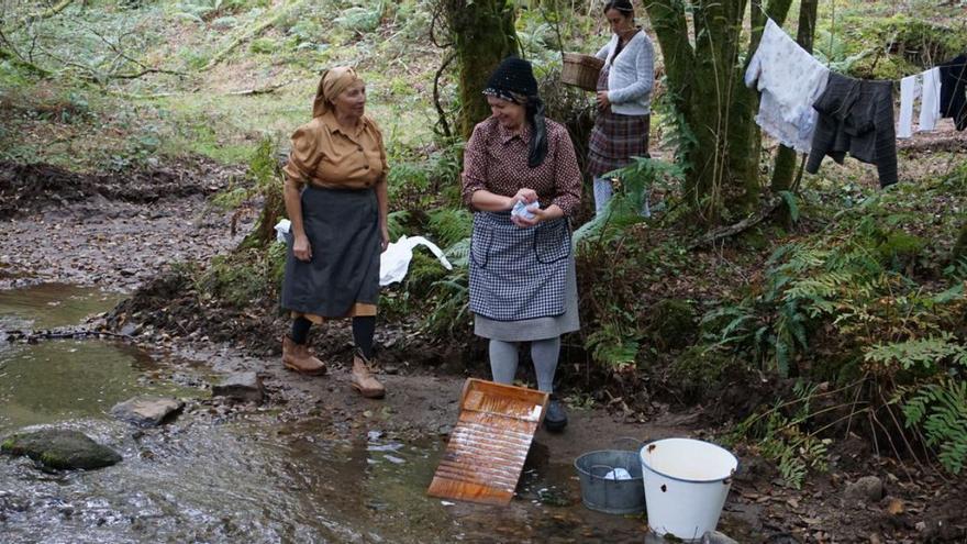 Unas mujeres recrean las labores de lavado de ropa a orillas del río en Vilasantar.   | // LA OPINIÓN