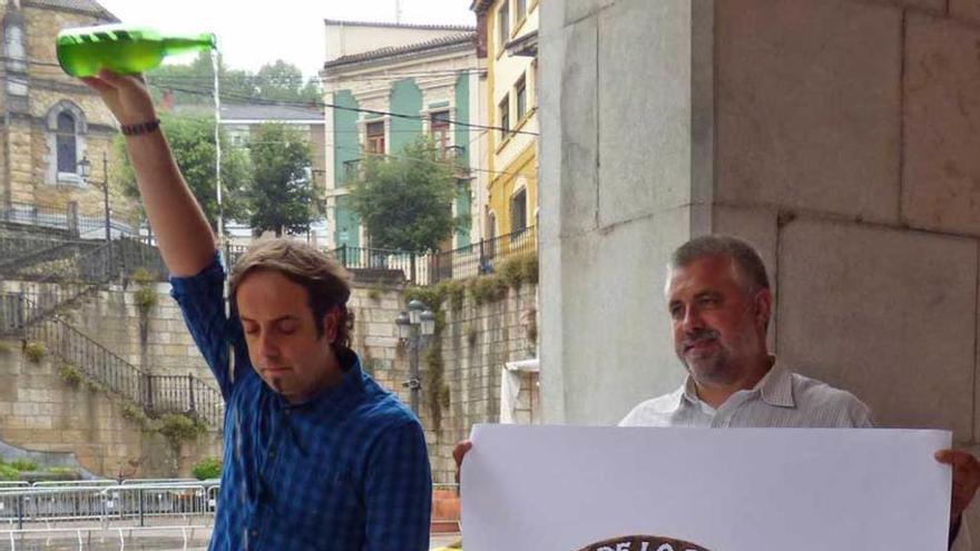 Luis Sariego escancia mientras Avelino Fuentes muestra el logo.