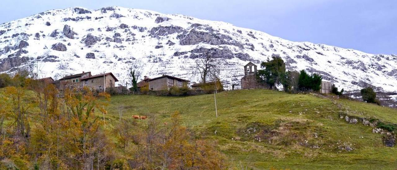 Casas e iglesia de Santa María, en el pueblo de Muriellos, con la montaña nevada al fondo.