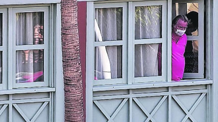 Un turista se asoma a la ventana de su habitación del H10 Costa Adeje.