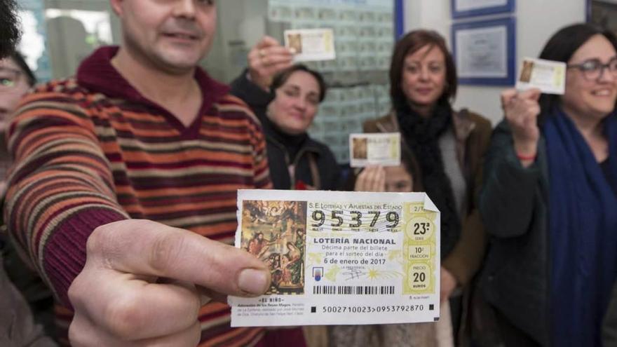 Un niño alza el décimo premiado vendido en un supermercado de A Lama (Galicia).