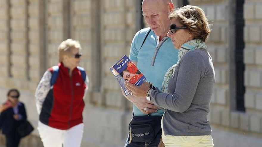 Turistas consultan una guía de Málaga en las inmediaciones de la Alcazaba y el Palacio de la Aduana.