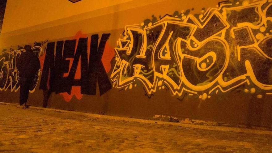 Un ciudadano pasea por el muro sobre el que pintó el grafitero detenido por la Policía Municipal.
