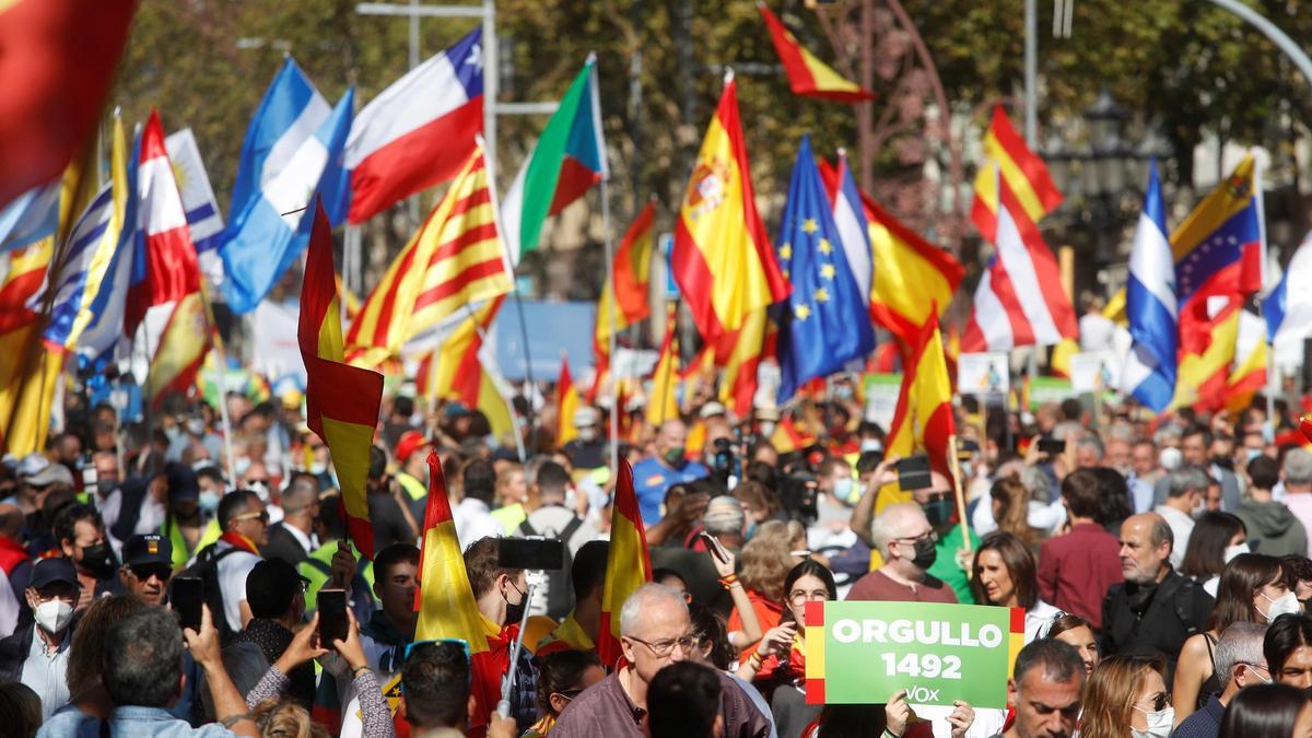 Varias personas muestran banderas de países latinoamericanos en la manifestación de Barcelona.