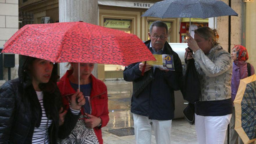 Turistas se protegen de la lluvia, este viernes en Málaga.