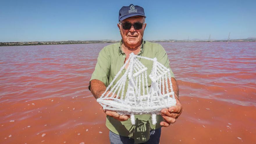 Manuel Sala muestra un barco de sal en el «charco» de la laguna rosa.