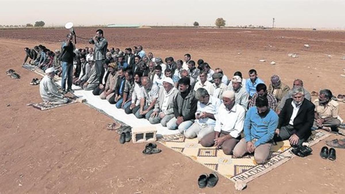 Un grupo de kurdos turcos rezan por el pueblo de Kobani en un campo en el sur de Turquía, ayer.