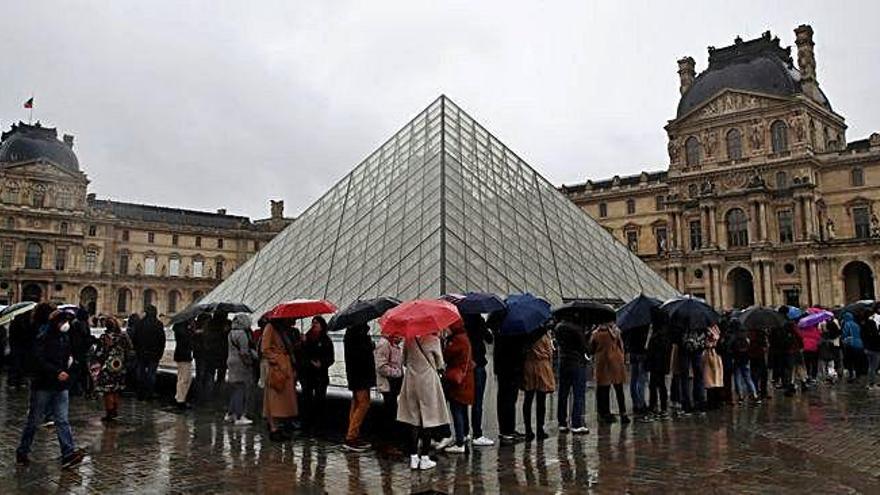 Decenas de personas hacen cola, ayer, junto a la mítica pirámide del Louvre.